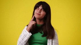 4k slow motion video of girl with thoughtful facial expression on yellow background.