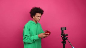 Portrait of a popular blogger recording a vlog. Close-up shot of young guy with ethnic hair using his smartphone to connect with followers. High quality 4k footage