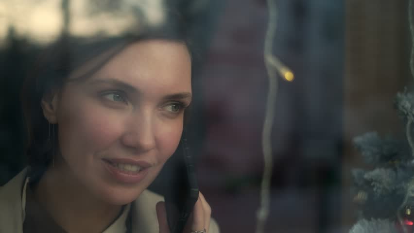 Close-up face of a confident serious business woman calling for work in a cafe using a mobile phone. A beautiful young woman with dark hair is talking on a smartphone. Close-up of a lady talking