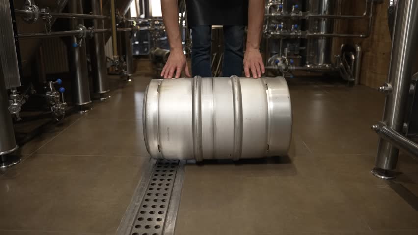 A man rolls a large steel barrel