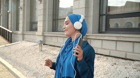 Middle eastern woman in hijab listening music with headphones and dancing. Woman independence and feminism concept. - Powered by Shutterstock - Get 15% off with code: PIKWIZARD15