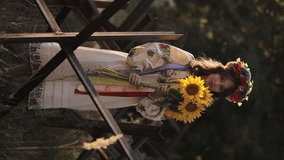 A beautiful Ukrainian girl in a Ukrainian national vyshyvanka dress with a bouquet of sunflowers against the background of anti-tank hedgehogs. war in Ukraine. War of Russia against Ukraine. - Powered by Shutterstock - Get 15% off with code: PIKWIZARD15