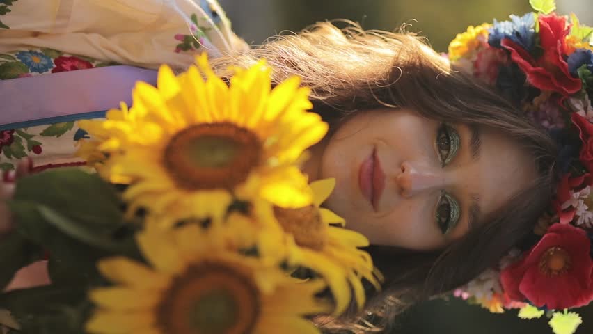 portrait of a Ukrainian woman in the Ukrainian national vyshyvanka dress with a bouquet of sunflowers against the background of anti-tank hedgehogs. close-up. War of Russia against Ukraine.