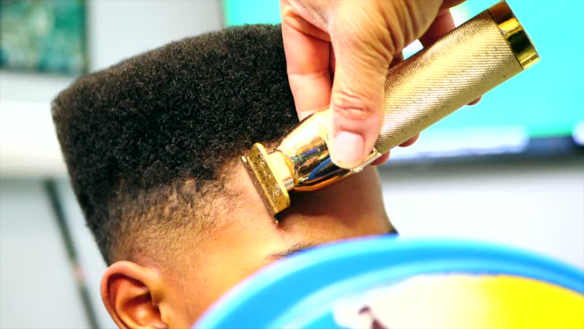 Close up static shot of barber doing line up haircut on black boy Royalty-Free Stock Footage #1099199067