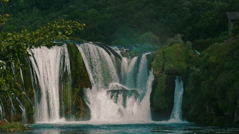 Majestic waterfall, surrounded by lush greenery, cascading water, misty spray, natural beauty, peaceful ambiance วิดีโอสต็อก