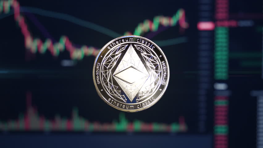 Ethereum Classic ETC crypto currency coin hovering in front of trading charts with light energy passing through | Shutterstock HD Video #1099201151