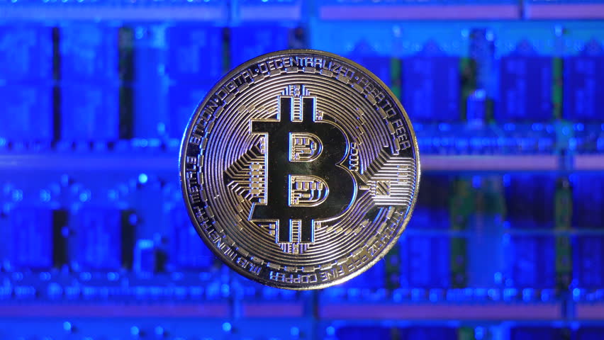 A Bitcoin BTC crypto currency coin hovering over a mining rig of computer chips and electric energy passing through | Shutterstock HD Video #1099201163