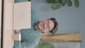 Vertical Video of Mature Adult Man Smiling at Camera while using Laptop - Powered by Shutterstock - Get 15% off with code: PIKWIZARD15