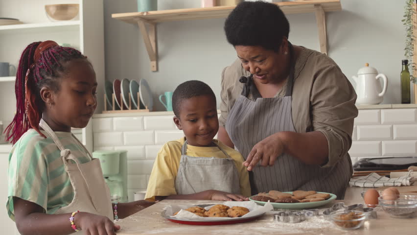 Two African American tween siblings trying homemade cookies just baked by their grandma | Shutterstock HD Video #1099207769