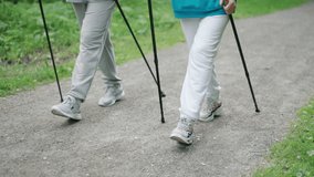 Persons walk scandinavian trekking sticks. People hold nordic poles in green forest park. Pair sport stroll. Man womans sneakers shoes close up. Hiker couple walking training. Nordic feet step closeup - Powered by Shutterstock - Get 15% off with code: PIKWIZARD15