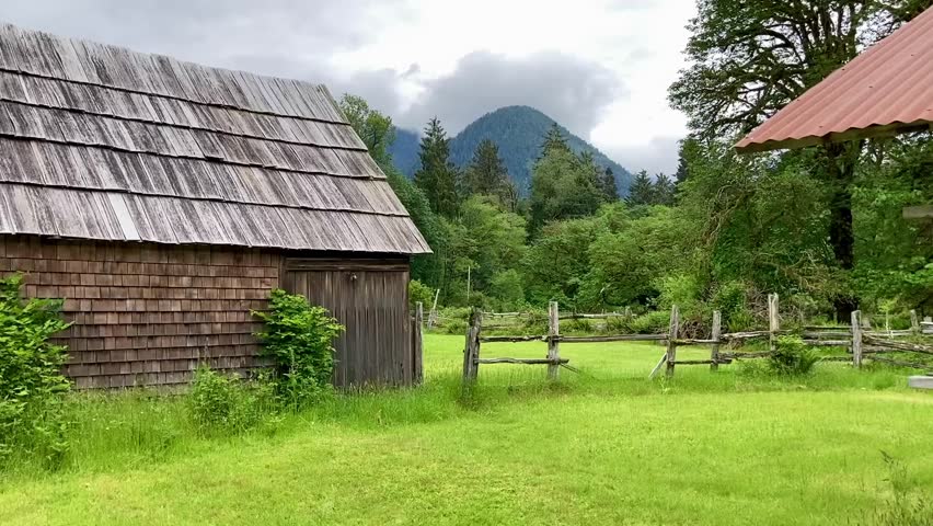 The abandoned wooden buildings of the Kestner Homestead with the beautiful mountains of the Olympic National Park in the background - Nr Quinault, Washington, USA
