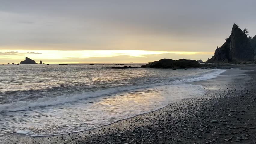 The sunset on Rialto Beach in the Olympic National Park with the waves gently lapping the shore, the rock stacks in the background and the orange sky on the horizon - Nr La Push, Washington, USA