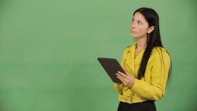 A young beautiful Caucasian woman works on a tablet - green screen studio - Powered by Shutterstock - Get 15% off with code: PIKWIZARD15