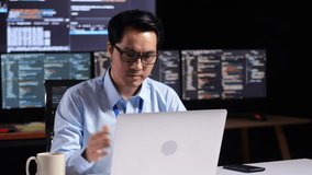 Asian Male Programmer Having A Meeting By A Laptop While Writing Code On Multiple Monitors Showing Database On Terminal Window Desktops In The Office
