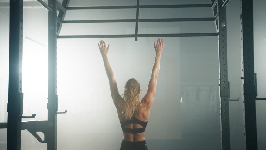 Back view of caucasian fitness girl during her morning workout session at the gym. Young, healthy woman using the pull up bar to train all muscle groups. High quality 4k footage Royalty-Free Stock Footage #1099217573