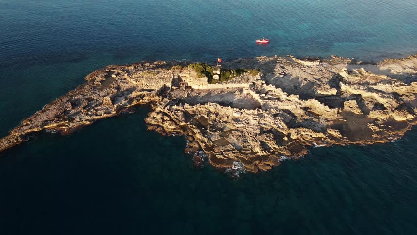 An aerial perspective of a rocky island in the Mediterranean sea near the coast of Turkey. The small, inhabited island offers seclusion and natural splendor, a perfect getaway from the hustle of city 