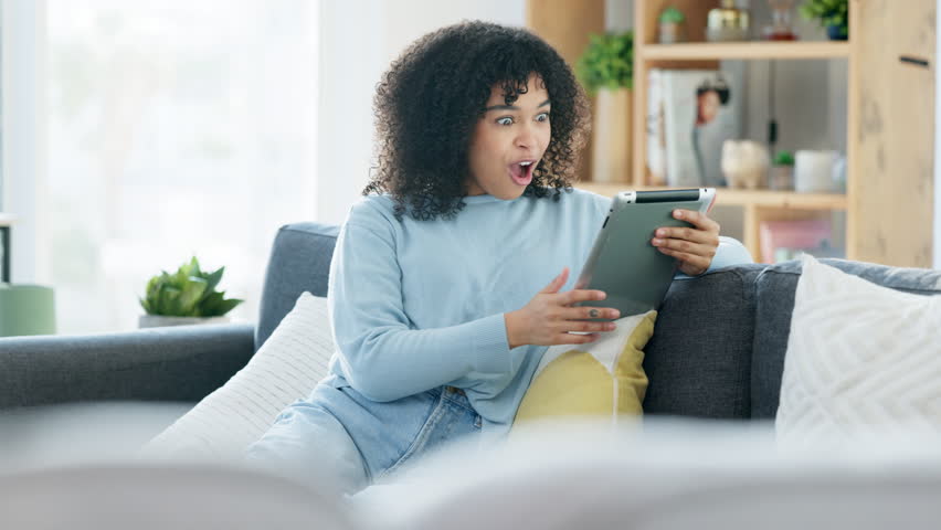 Excited woman relaxing and talking on her tablet. Technology and innovation aids people from a distance. Casual, happy and free afro lady laughing while speaking with their friend online and indoors. | Shutterstock HD Video #1099222589