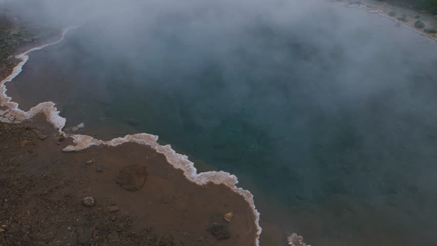 Natural geyser in Iceland. Landmarks of the golden ring in Iceland. Hot water in the geyser crater in winter