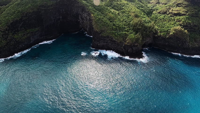 Aerial View of Blue Coastline and Crashing Waves along Rolling Hills in Kauai Hawaii Royalty-Free Stock Footage #1099227981
