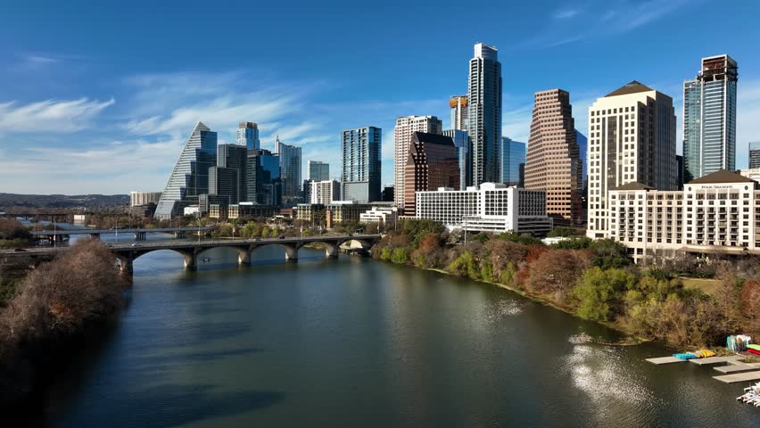 Aerial view low over the river, towards high-rise, sunny, fall day in Austin, USA