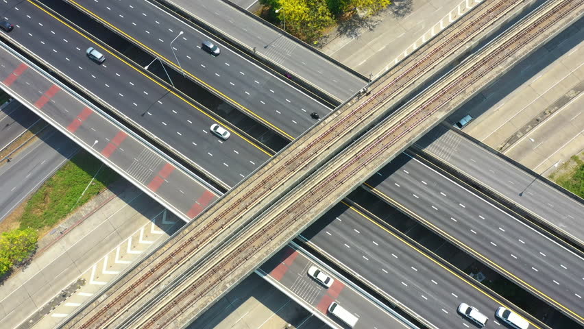 Aerial top View of railway track with electric train running, busy freeway, traffic on highway. Aerial view of multiple roads in city, vehicular intersection, expressway with important infrastructure. Royalty-Free Stock Footage #1099230397