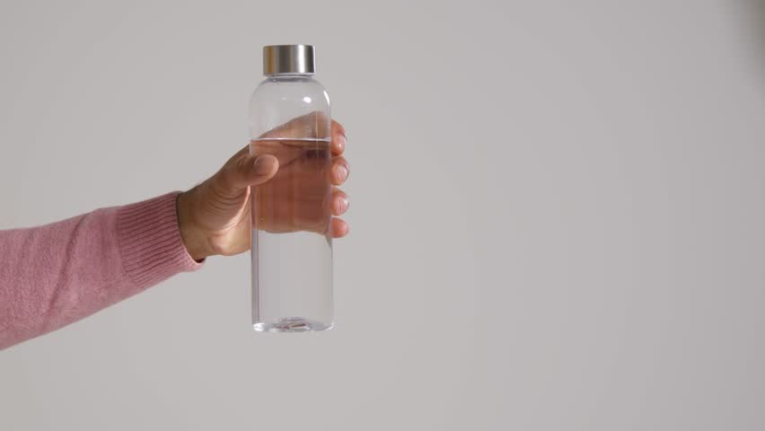 A mid shot of a man holding up a bottle of water to the camera. | Shutterstock HD Video #1099231043