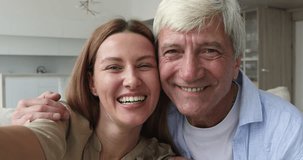 Selfie of pretty adult daughter woman and old mature dad holding gadget with webcam in hand, smiling at camera, laughing, making video call, hugging with love, having fun, enjoying family leisure