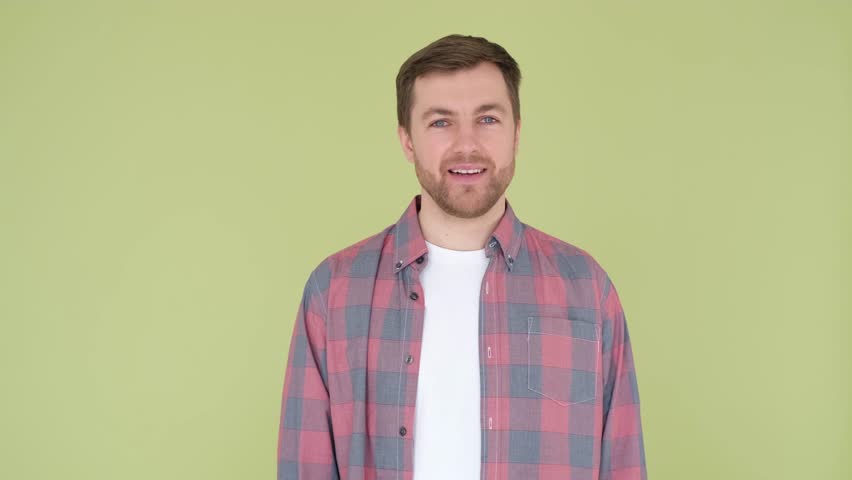 A handsome guy on an olive background flirts, spreads his arms | Shutterstock HD Video #1099243317
