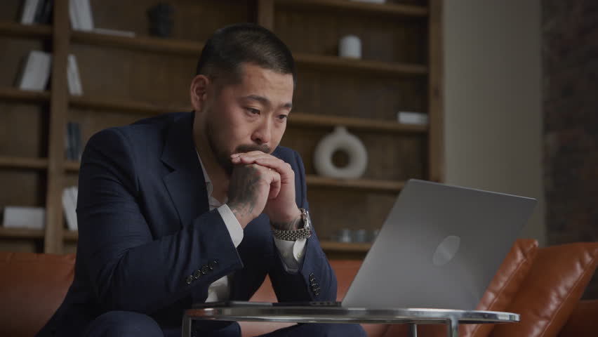 Thoughtful tattooed businessman. Pensive Asian man in a suit | Shutterstock HD Video #1099243671