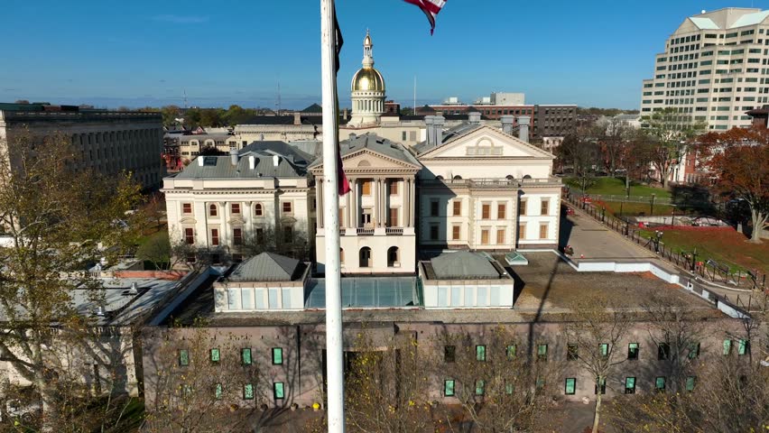 Trenton New Jersey State House capitol building in NJ. USA flag on winter autumn day. Rising aerial view.