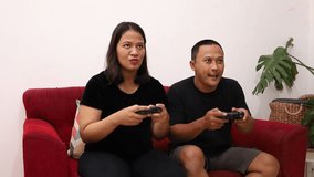 Happy young couple, pregnant wife and husband playing video game with joysticks on console. Cheerful family spending leisure time together during pregnancy