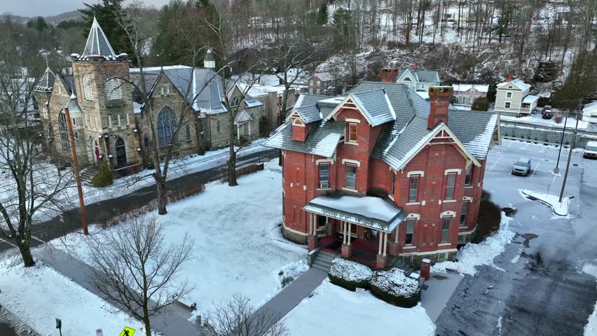 Slow aerial of Victorian house and church during snow storm. Gothic and historical buildings in New England states in America.
