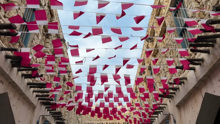 Wooden design building in Doha old city mudbrick adobe stone traditional houses designed by colorful Qatar flag tourists with Morocco Fan flag at day sun shining wind waving the hospitality of local