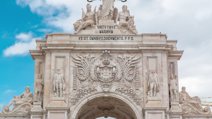 Top of Triumphal arch at Rua Augusta at Commerce square close up view timelapse in Lisbon, Portugal. Cloudy sky behind statues