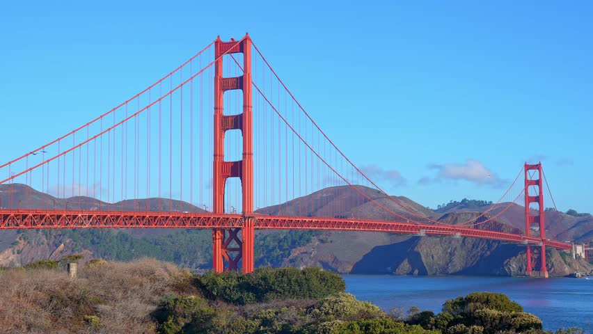 View of historic Golden Gate Suspension Bridge over San Francisco Bay with clear blue sky in the background during sunny day