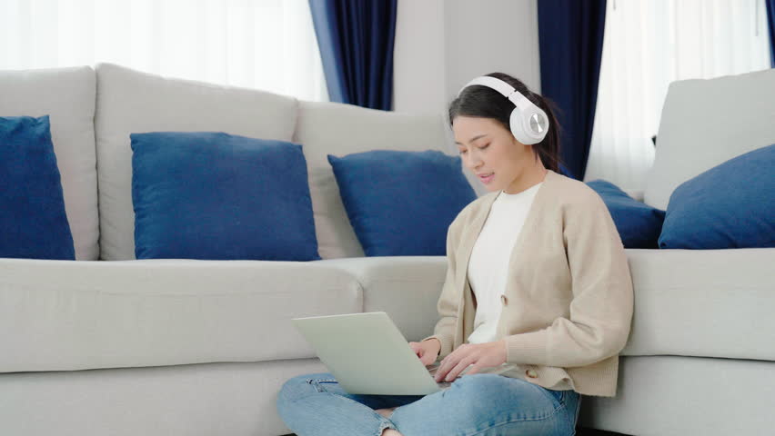 Young asian woman wearing headset while working on computer laptop at house. Work at home, Video conference, Video call, Student learning online class | Shutterstock HD Video #1099259793