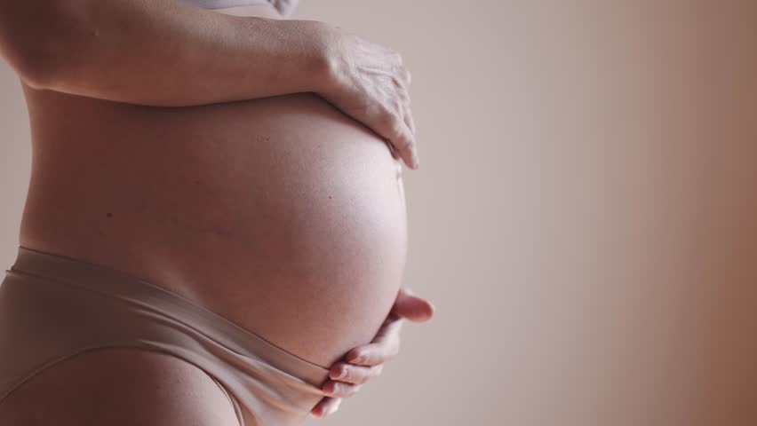 Pregnant woman. health pregnancy motherhood procreation concept. close-up belly of a pregnant woman. woman waiting for a newborn baby. pregnant indoors woman holding her belly sunlight | Shutterstock HD Video #1099264193