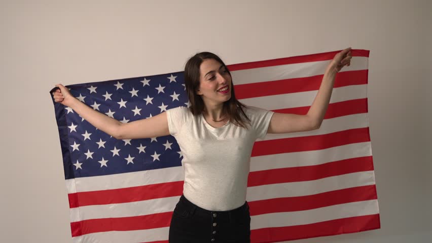 caucasian woman smiling embraced with usa flag isolated on a white background