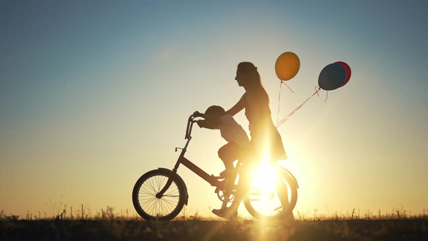 Mom teaches son to ride a bike. happy family childhood dream concept. mom sunlight and little son learn to ride a bike silhouette in the park in nature. happy family goes in for sports outdoors | Shutterstock HD Video #1099269077