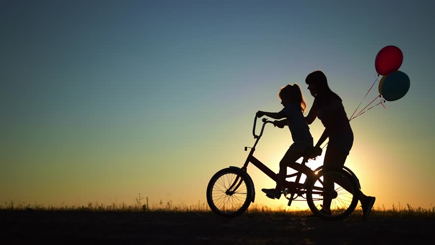 mom teaches daughter to ride a bike. happy family childhood dream concept. mom and little daughter learn to ride a bike silhouette in park in nature. happy family goes in for sports outdoors sunlight Royalty-Free Stock Footage #1099269083