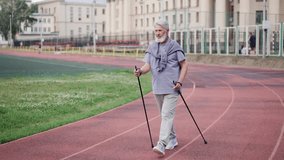 Elderly man practice nordic walk. Senior old sportsman scandinavian pole hike stadium. Grandpa workout sport Europe. Healthy men lifestyle. Old pensioner people smile. Elder grandfather walking park. - Powered by Shutterstock - Get 15% off with code: PIKWIZARD15