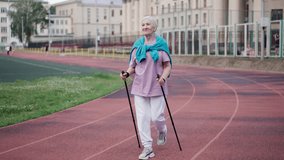 Elderly woman practice nordic walk. Senior old lady scandinavian pole hike stadium. Grandma sport workout Europe. Healthy women lifestyle. Old pensioner people smile. Elder grandmother walking park. - Powered by Shutterstock - Get 15% off with code: PIKWIZARD15