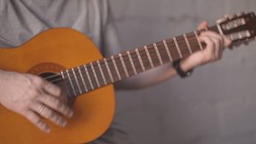a man in a gray T-shirt rhythmically plays the guitar. High quality Full HD video recording