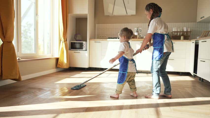 Happy children at home mopping floors.Clean house cleaning.Cute child work at home.Clean interior.Domesticated child washes floors with mop.Completion of assigned task.Teaching children about homework | Shutterstock HD Video #1099280431