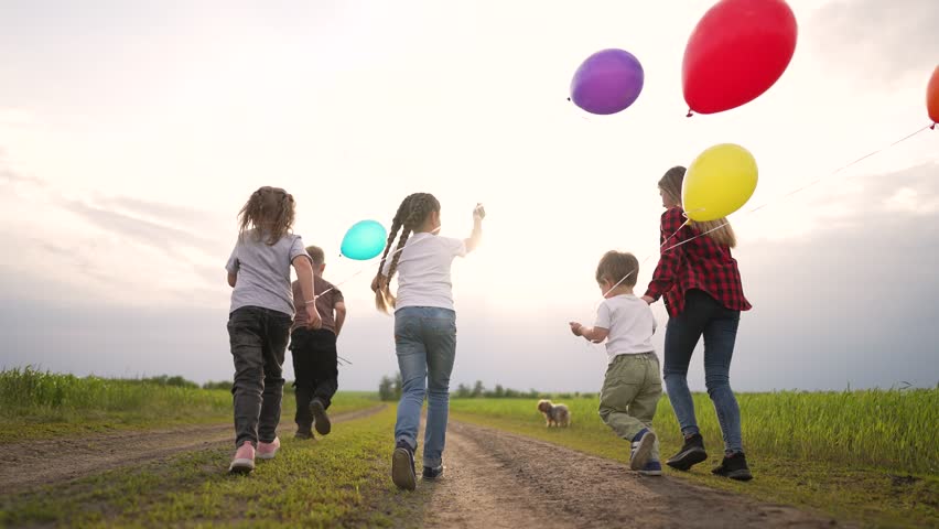 Kids are having fun playing in backyard. Happy family runs with balloons in park. Cheerful smile of children playing in park in nature. Freedom in summer group of children run together with balloons | Shutterstock HD Video #1099280443