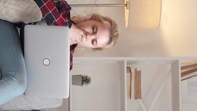Vertical video. Inspired relationship. Happy couple. Internet support. Handsome man in headphones helping woman to working laptop light room interior.