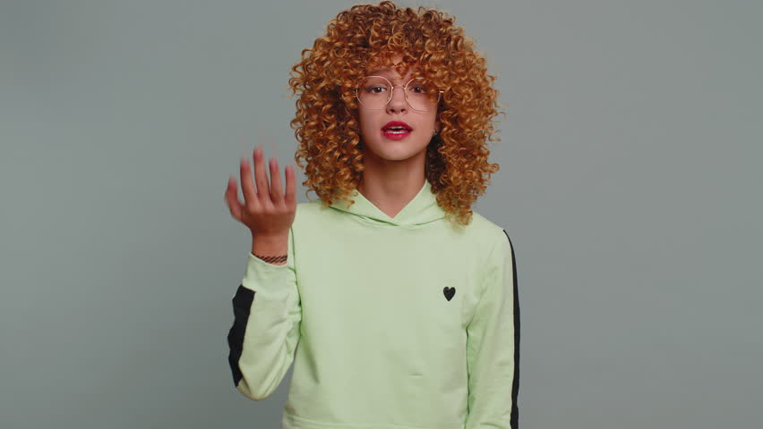 Young child girl kid with curly hair shakes finger and saying no, be careful, scolding and giving advice to avoid danger mistake, disapproval sign. Teenager children alone on studio gray background | Shutterstock HD Video #1099285229