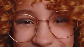 Extreme close-up macro portrait of smiling girl face. Teen beautiful kid's eyes, looking at camera. Brown eyes of redhead female child model. Young children in eyeglasses opening wide her closed eyes - Powered by Shutterstock - Get 15% off with code: PIKWIZARD15
