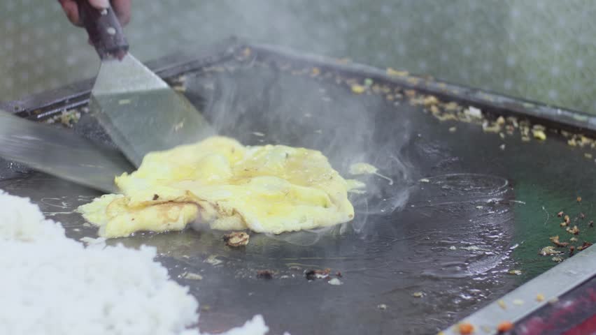 Selective focus on the omelet that is being fried and sold at the culinary festival at night. with motion blur effect | Shutterstock HD Video #1099289409