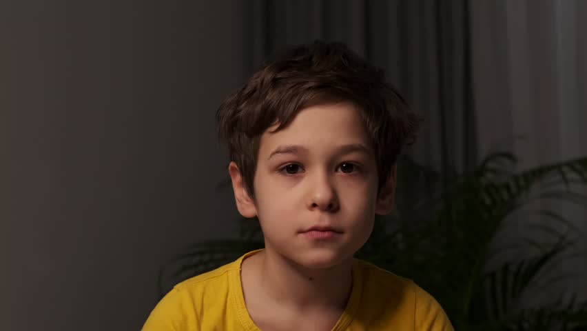 portrait close up face of a sad boy with black eyes in a dark room. child safety concept. Royalty-Free Stock Footage #1099294591